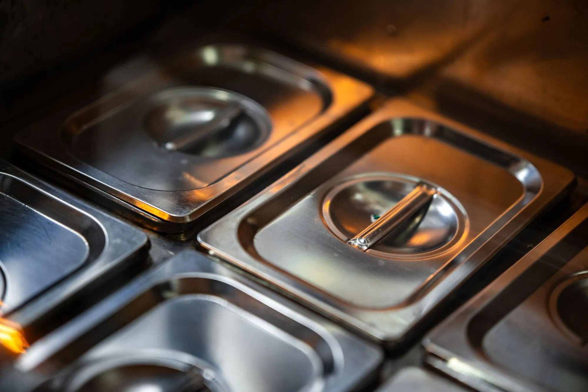 Lidded stainless steel food containers on a prep counter